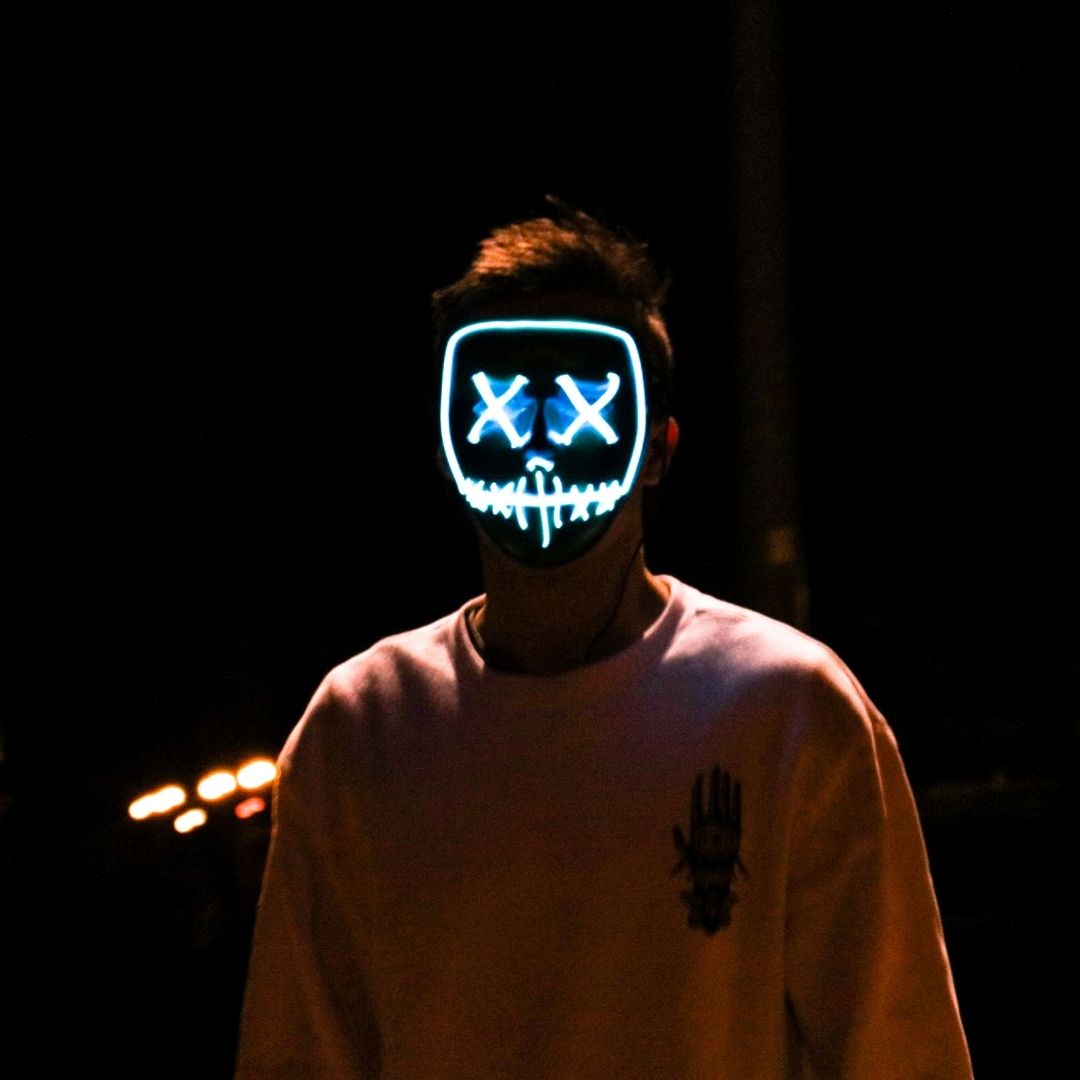 A light painting of a face with X's for eyes on a man standing in the dark