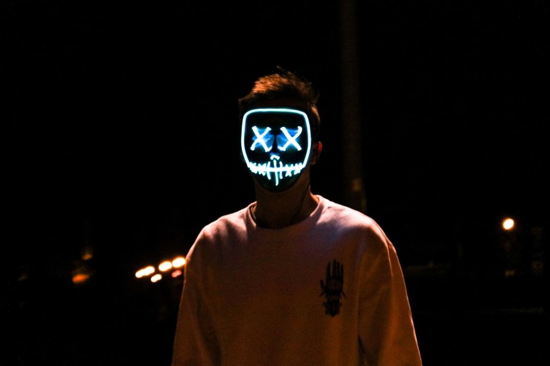 A light painting of a face with X's for eyes on a man standing in the dark