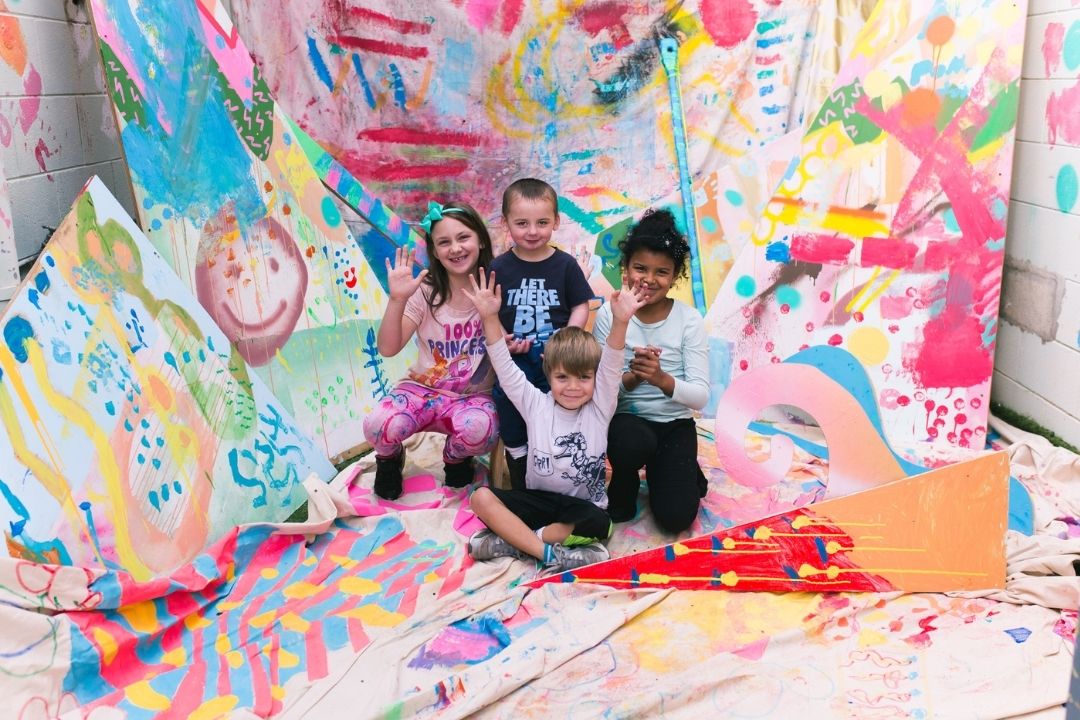 Four children in the Pom Pom studio in front of painted sheets