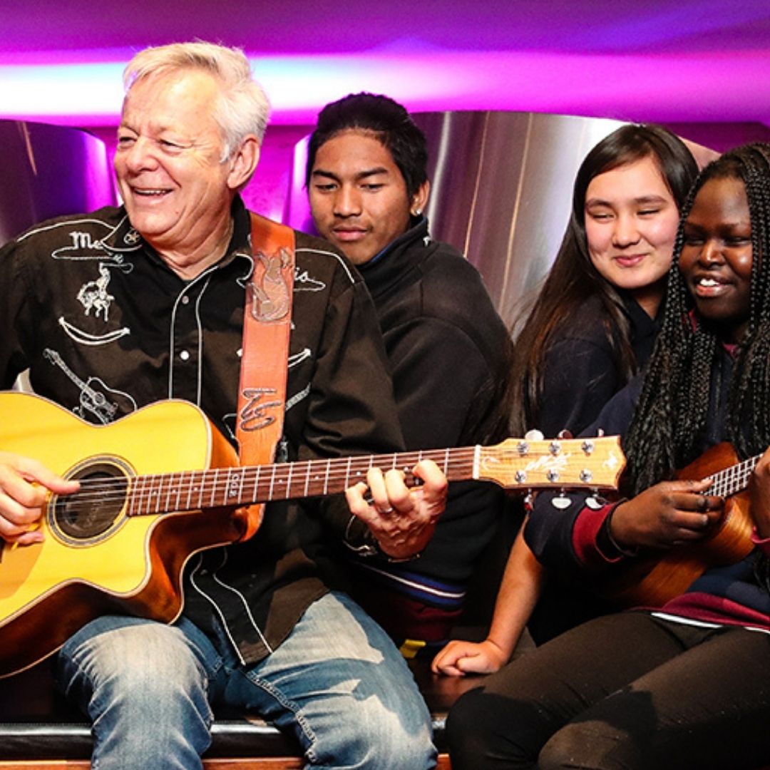 Guitarist Tommy Emmanuel playing with three aspiring young guitarists
