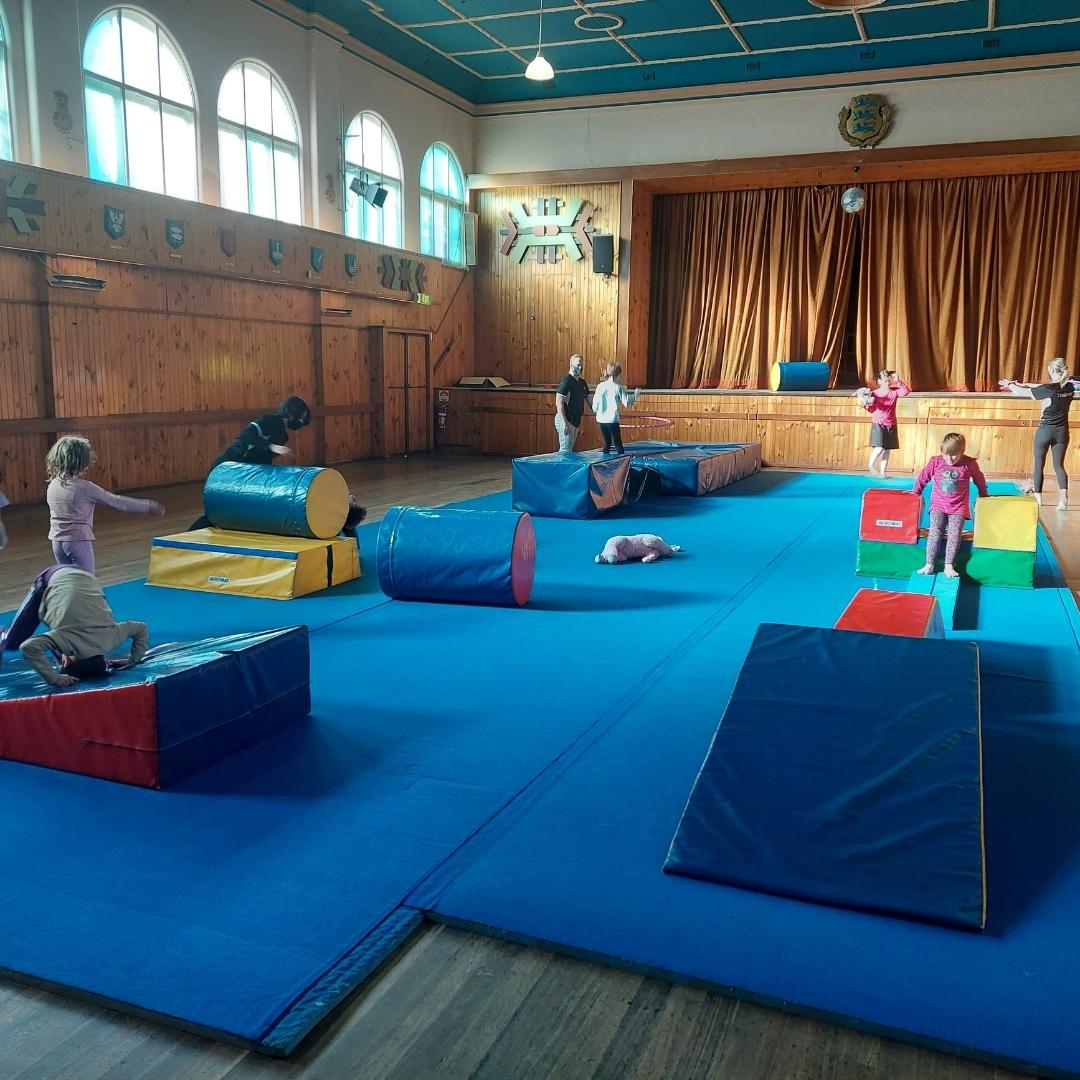 Children practicing circus on gym mats in a hall